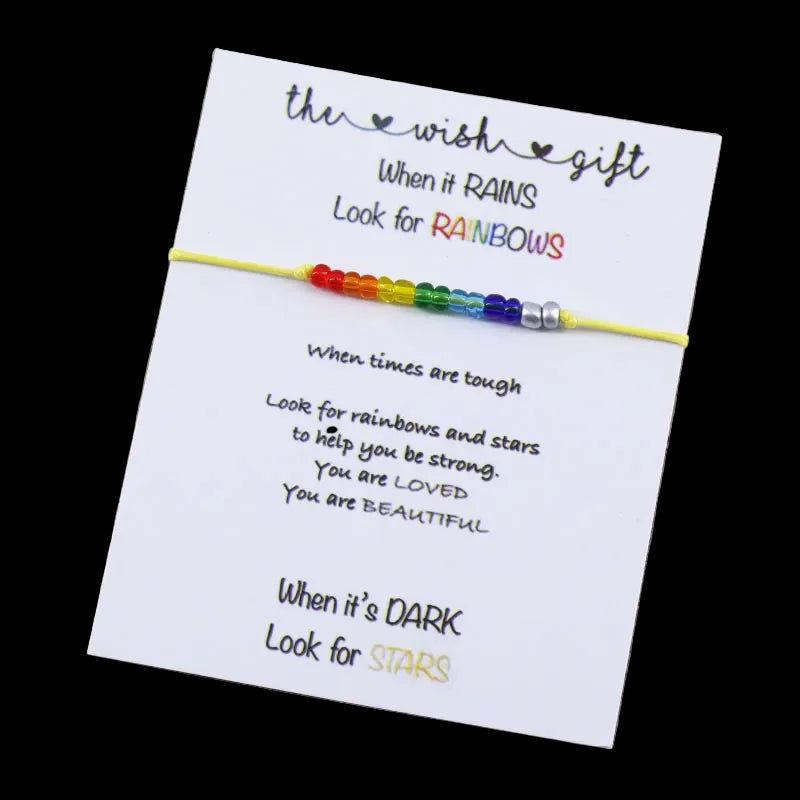 Rainbow beaded bracelet on a card with motivational text on a wooden surface