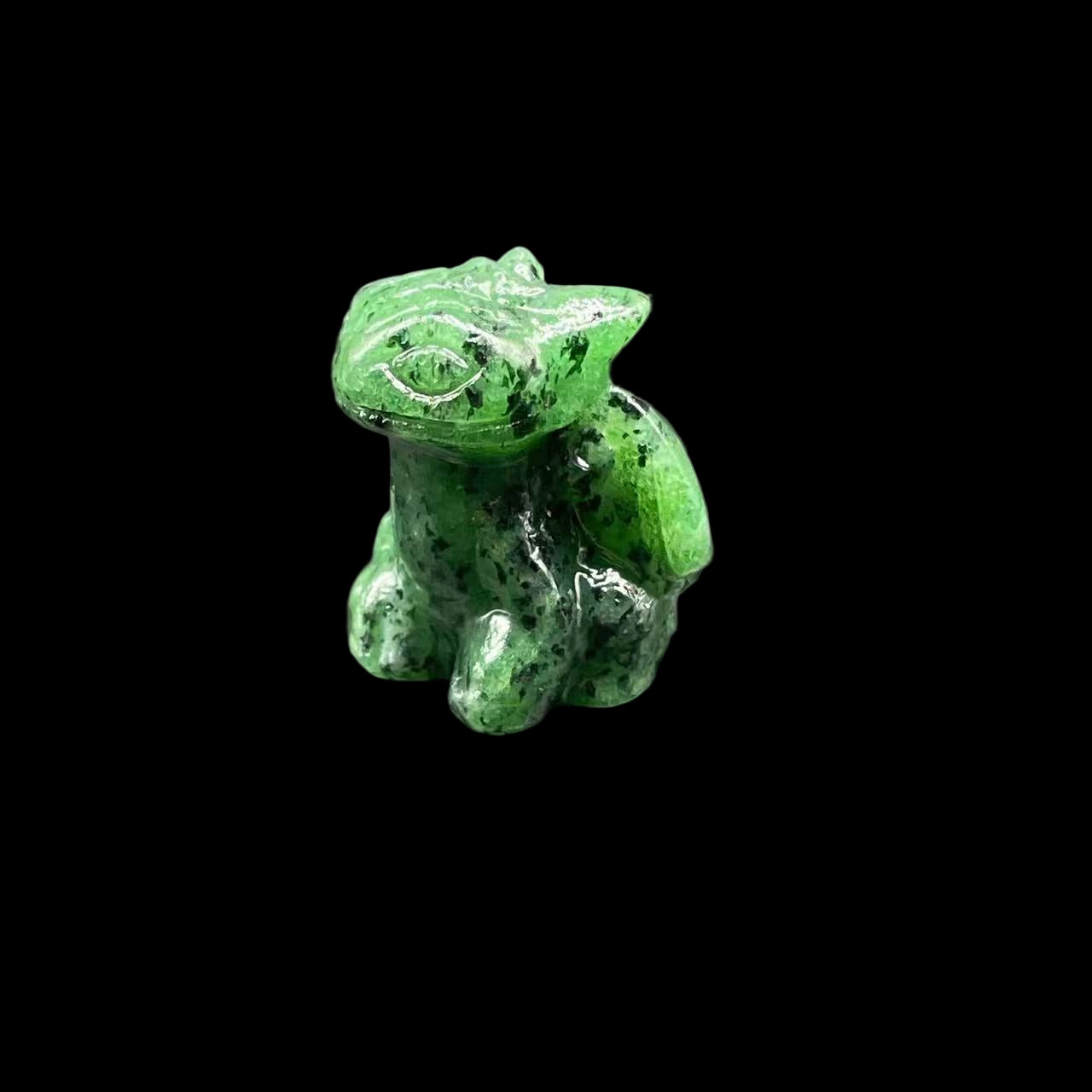 Green crystal frog figurine on a dark gray surface