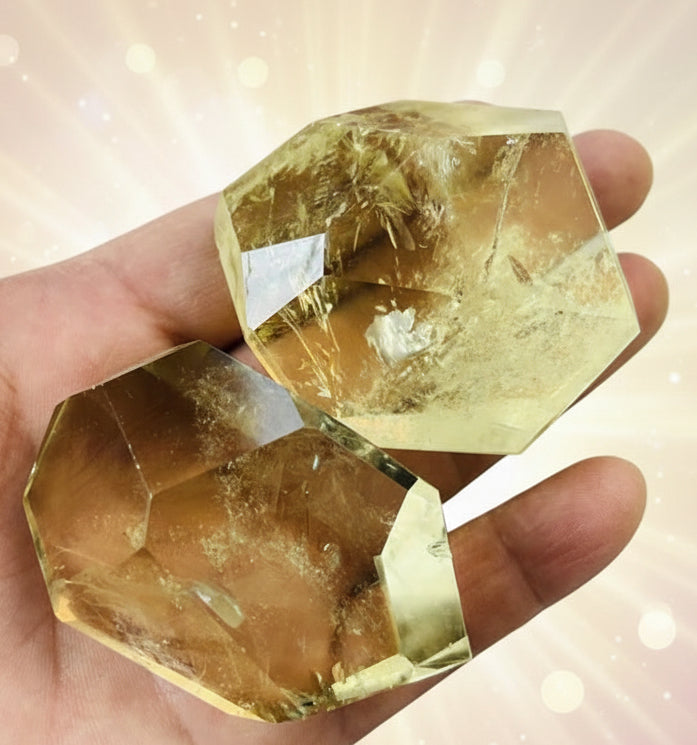 Hand holding two large, faceted yellow crystals with a blurred background