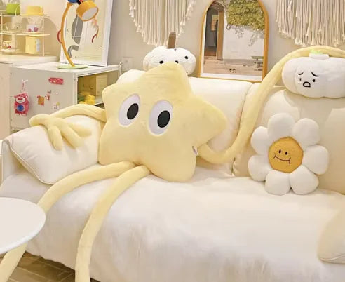Plush toy resembling a starfish with a flower face on a bed in a room setting.