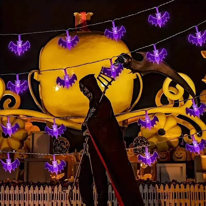 Halloween-themed decoration with a large pumpkin, purple bats, and a silhouette of a person in a hooded cloak.