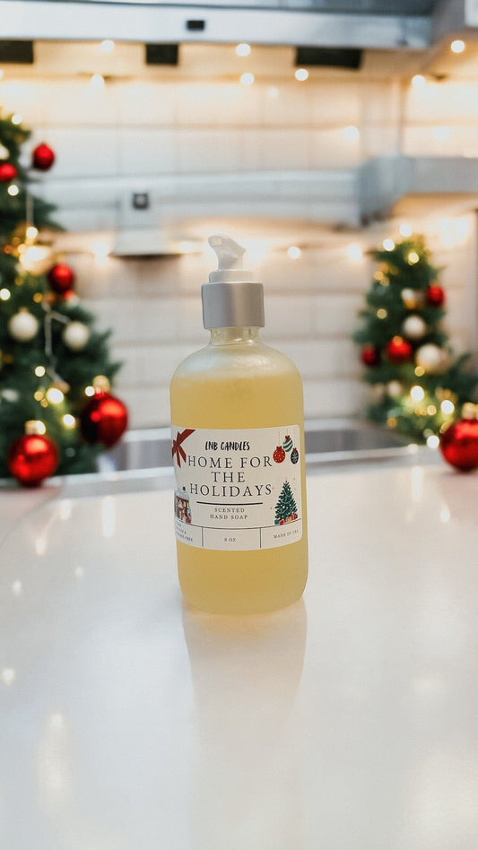 Bottle of soap with a Christmas-themed label on a kitchen counter with decorated trees in the background.