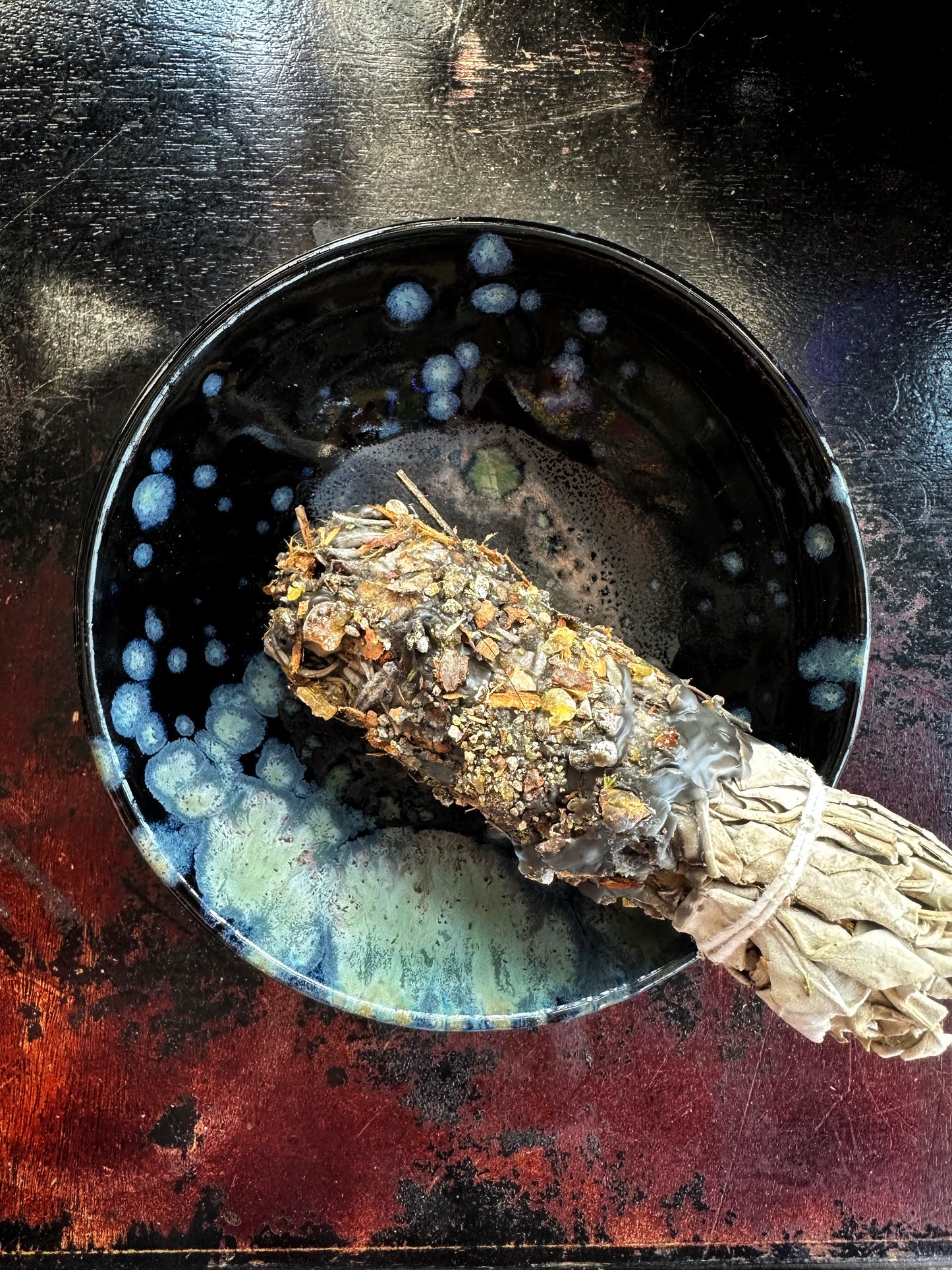 Sage bundle on a dark surface with a bowl of water