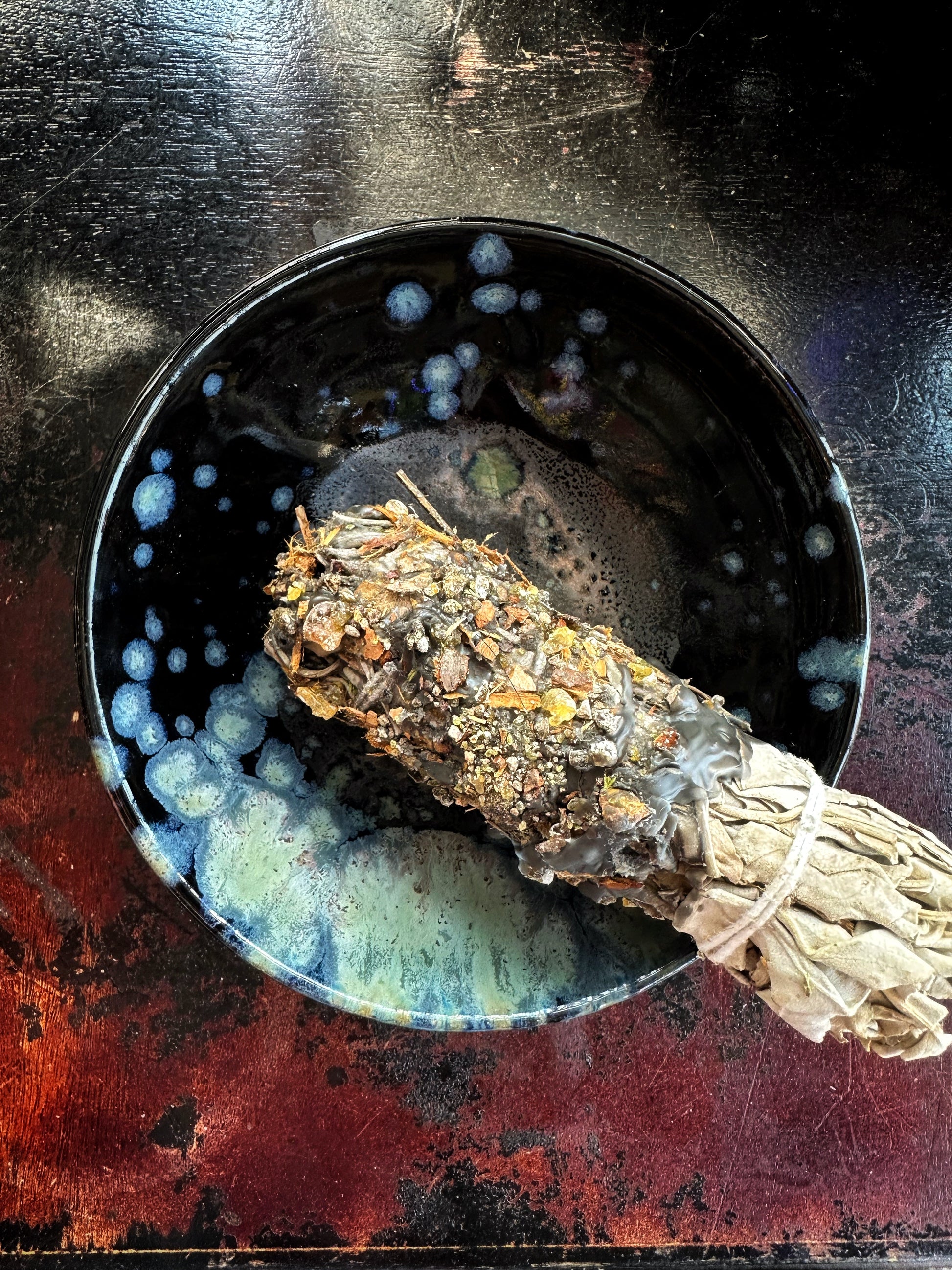Sage bundle on a dark surface with a bowl of water