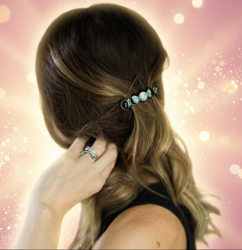 Person adjusting hair with a decorative hairpin, blurred background