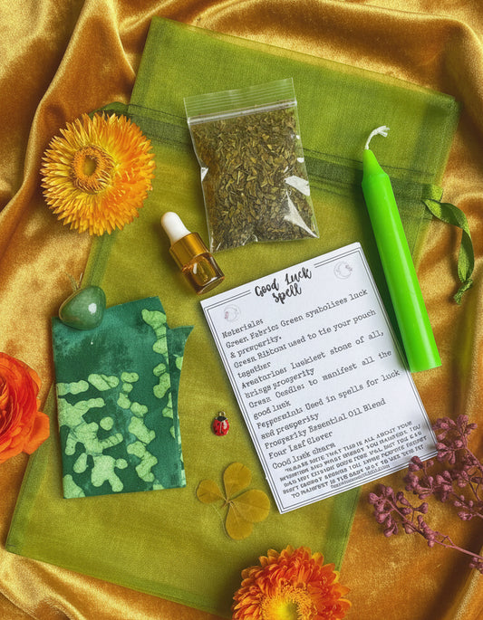 Herbal items, a candle, and a card on a green fabric with flowers and a turquoise background