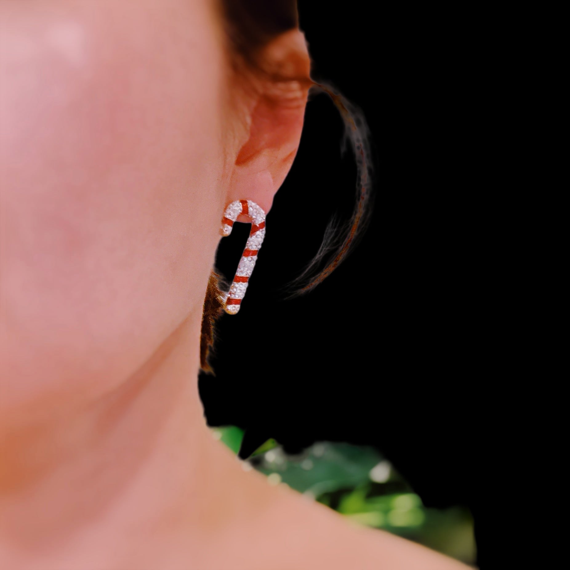 Close-up of a person wearing a white shirt with a red and white pattern, standing in front of green plants.