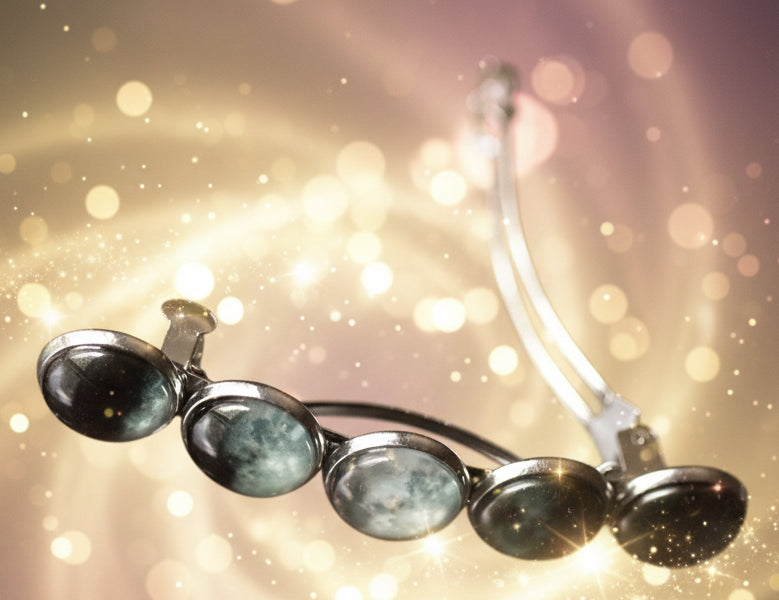 Silver earrings with dark stones on a reflective surface