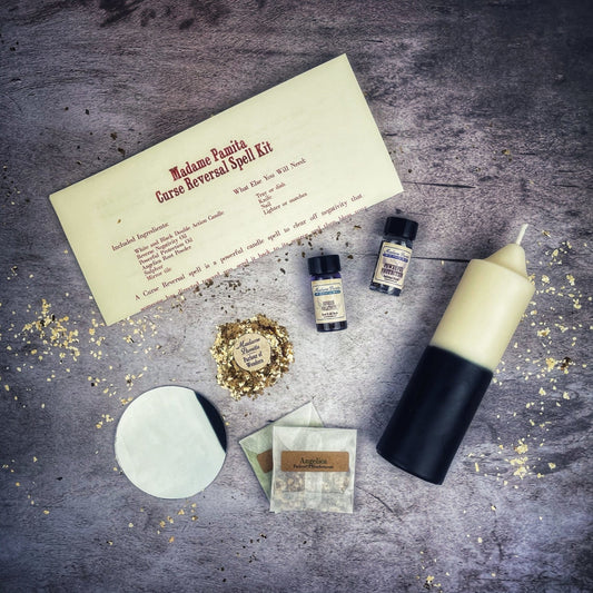 Spell kit with a candle, bottles, and a piece of paper on a textured surface