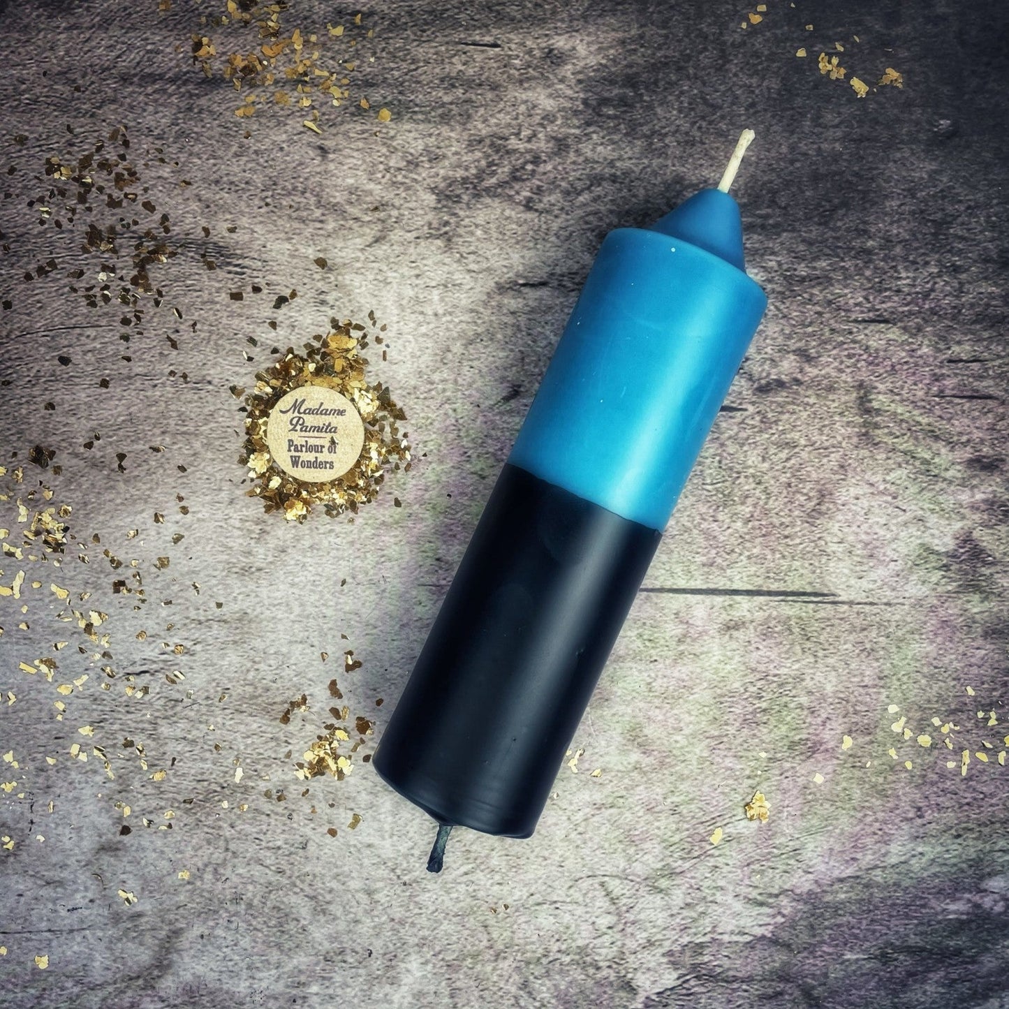 Blue and black cylindrical object on a textured surface with gold confetti