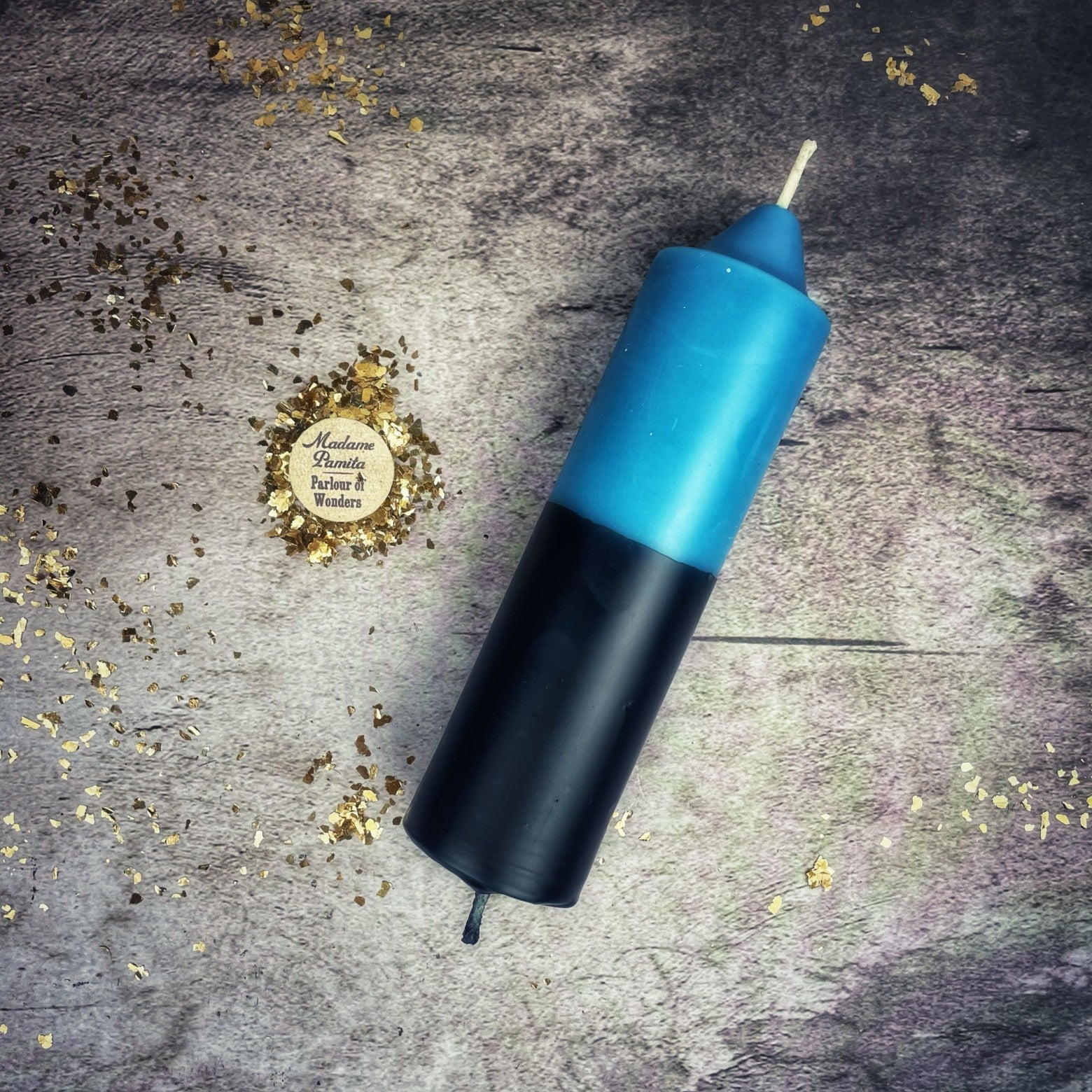 Blue and black cylindrical object on a textured surface with gold confetti