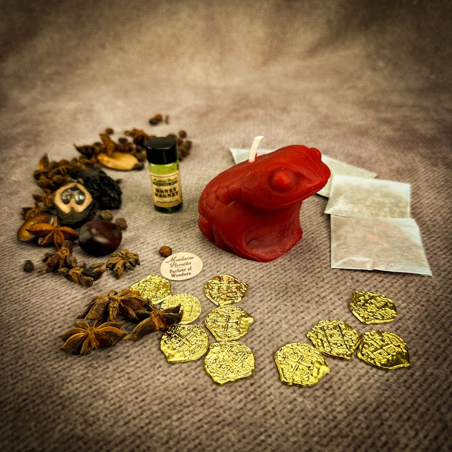 Spices, a red candle, gold coins, and a bottle on a textured surface