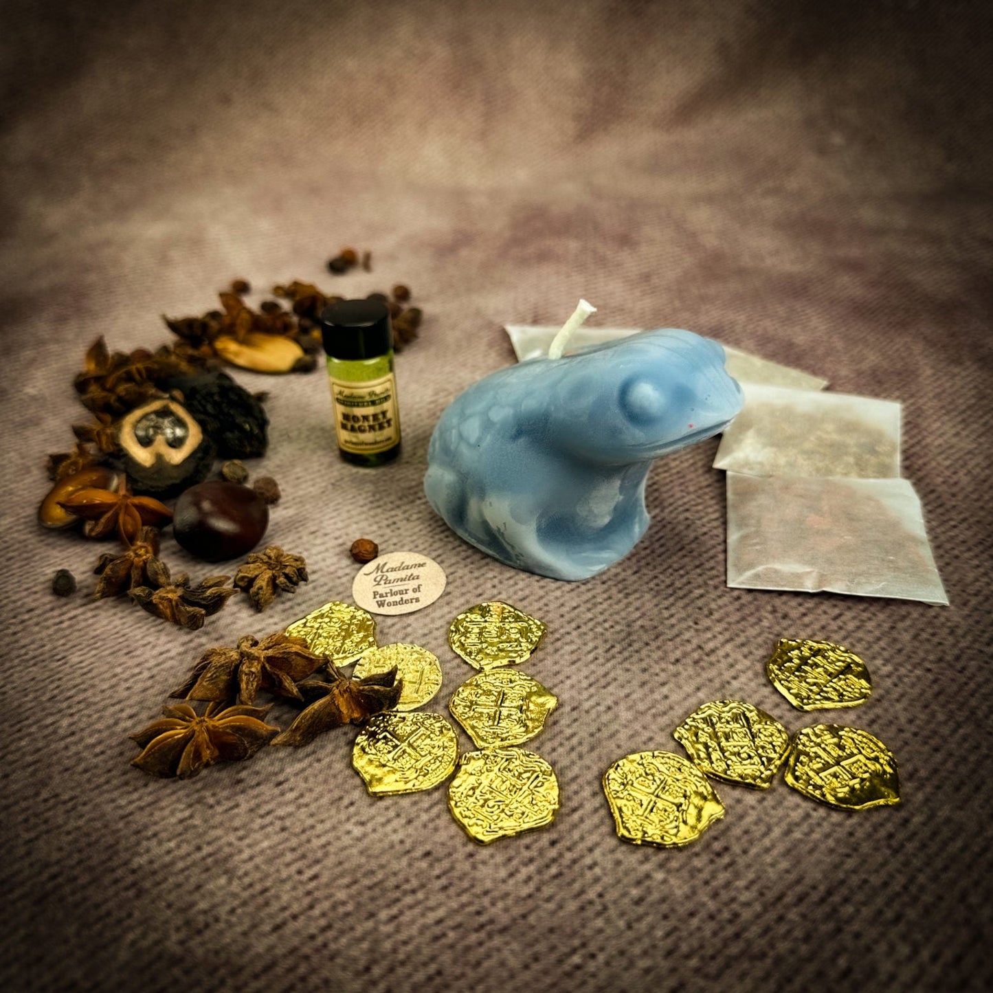 Assorted items including gold coins, a blue object, and dried herbs on a textured surface.