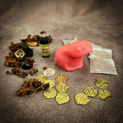 Spices, gold coins, a pink candle, and a bottle on a textured surface