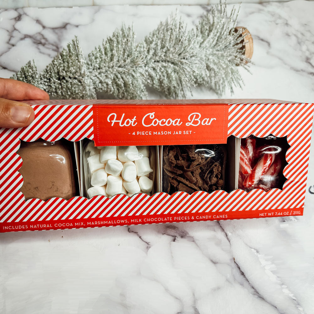 Hot cocoa bar set packaging with festive design on a marble surface