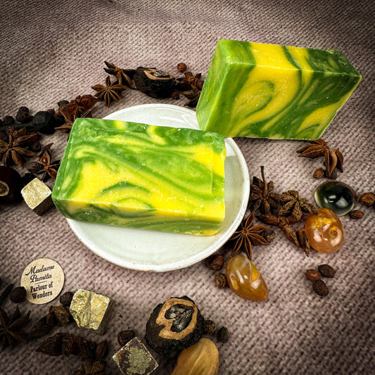Two green and yellow marbled soap bars on a textured surface with star anise and other spices.