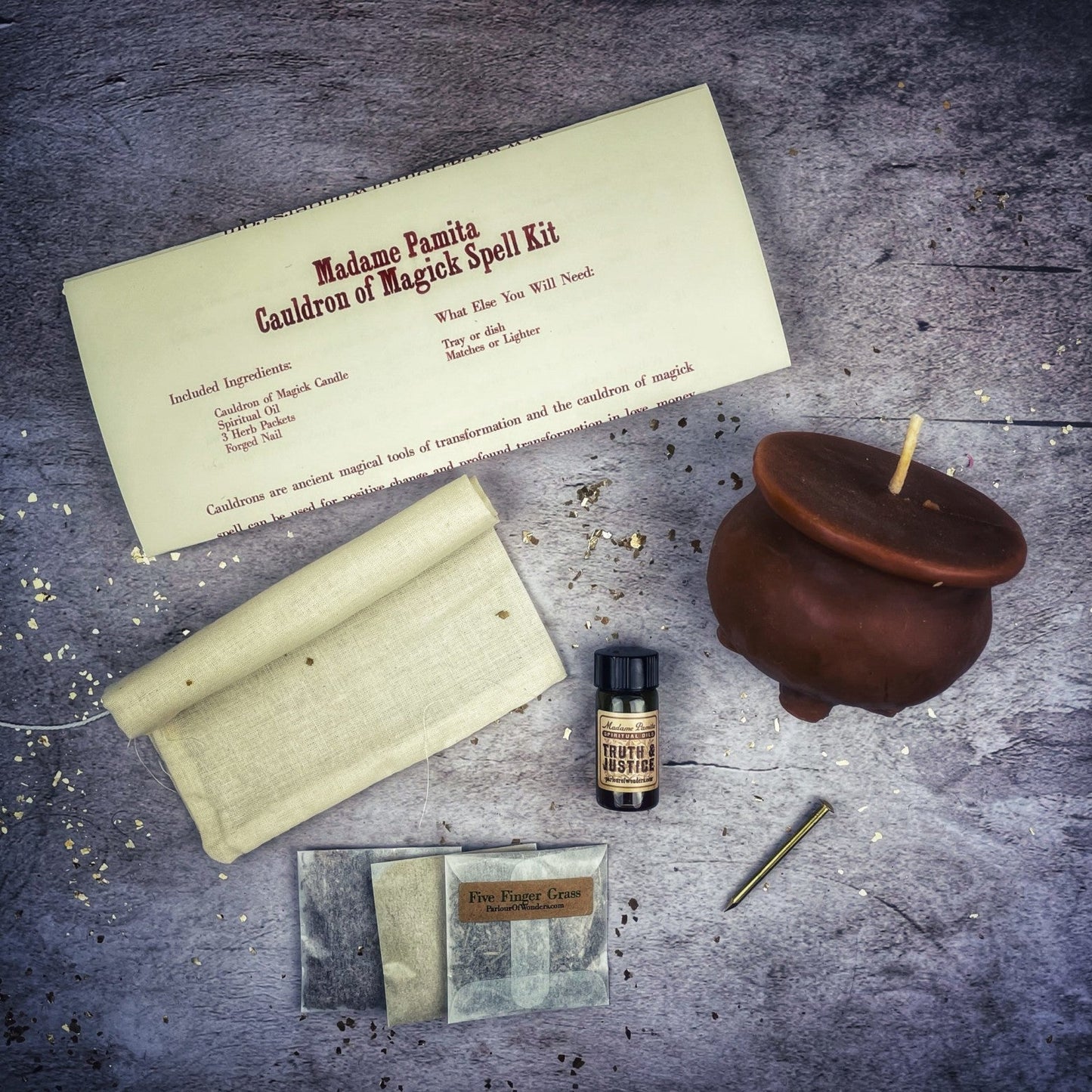 Magical spell kit with a candle, bottle, and paper on a dark surface