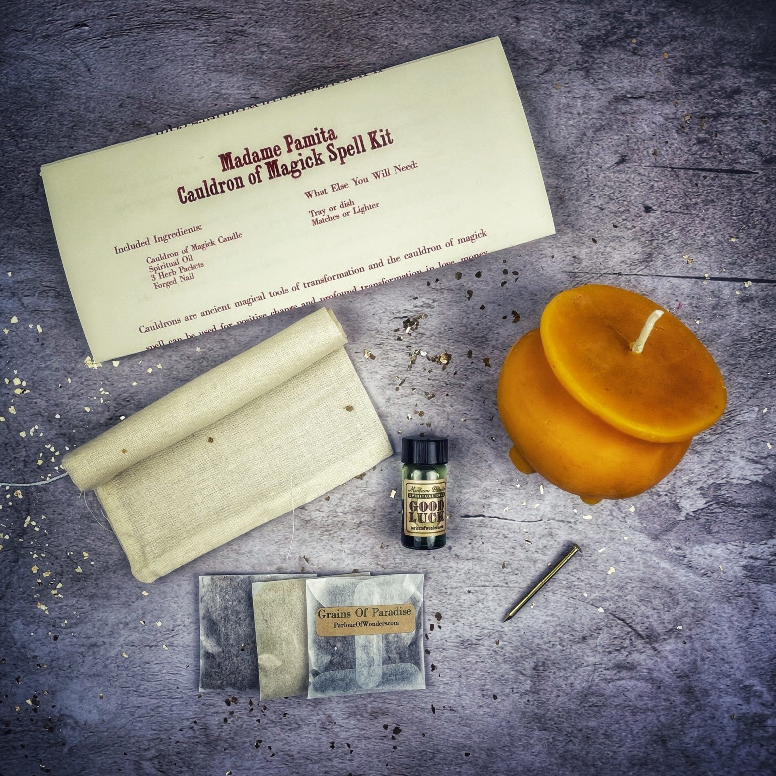 Magick spell kit with candles, scroll, and bottle on a textured surface