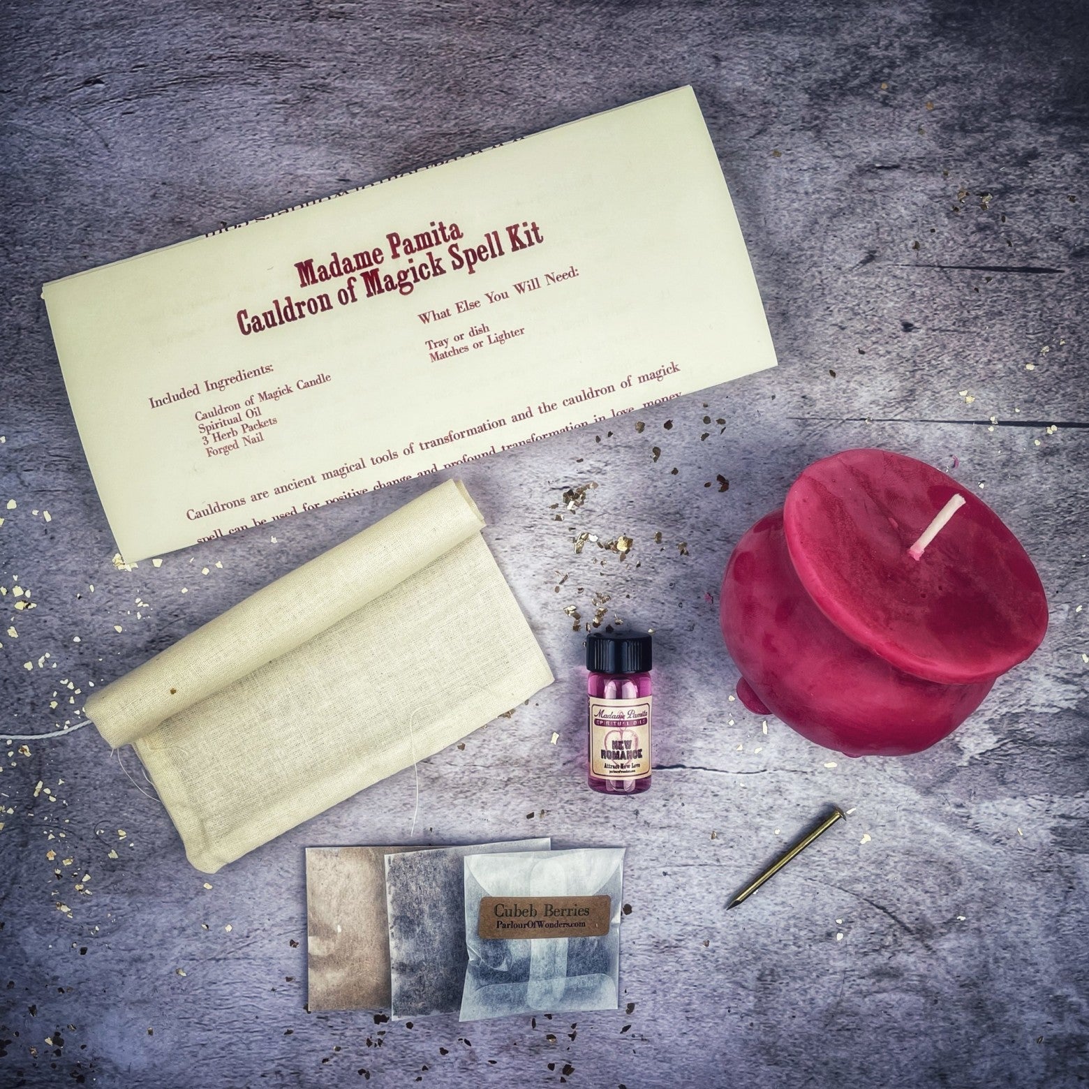 Magical spell kit with a red candle, scroll, and other items on a textured surface