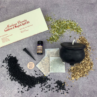 Witchcraft supply kit with a black cauldron, herbs, and a bottle on a gray surface.