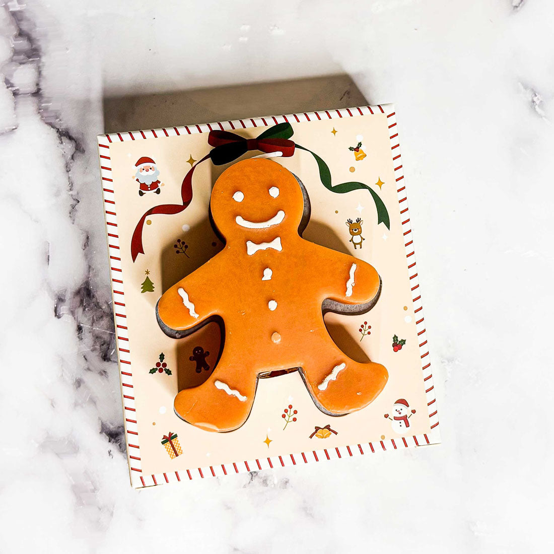 Gingerbread man cookie on a decorative card with Christmas elements on a marble surface