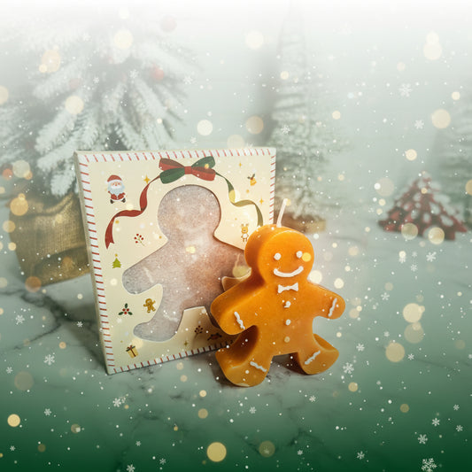 Gingerbread man candle next to a decorative gingerbread man card on a marble surface.