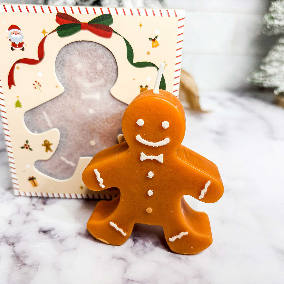 Gingerbread man candle with a decorative box on a marble surface