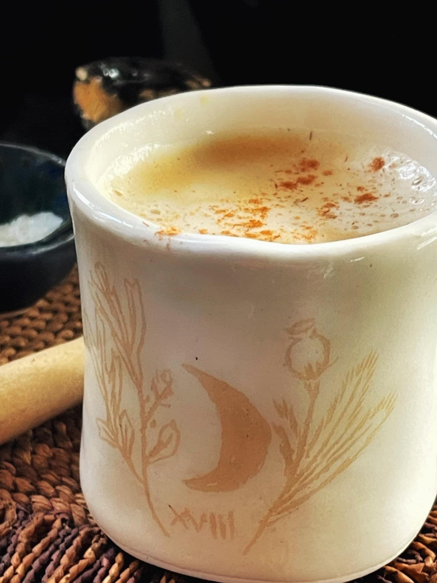White ceramic mug with decorative elements on a woven surface