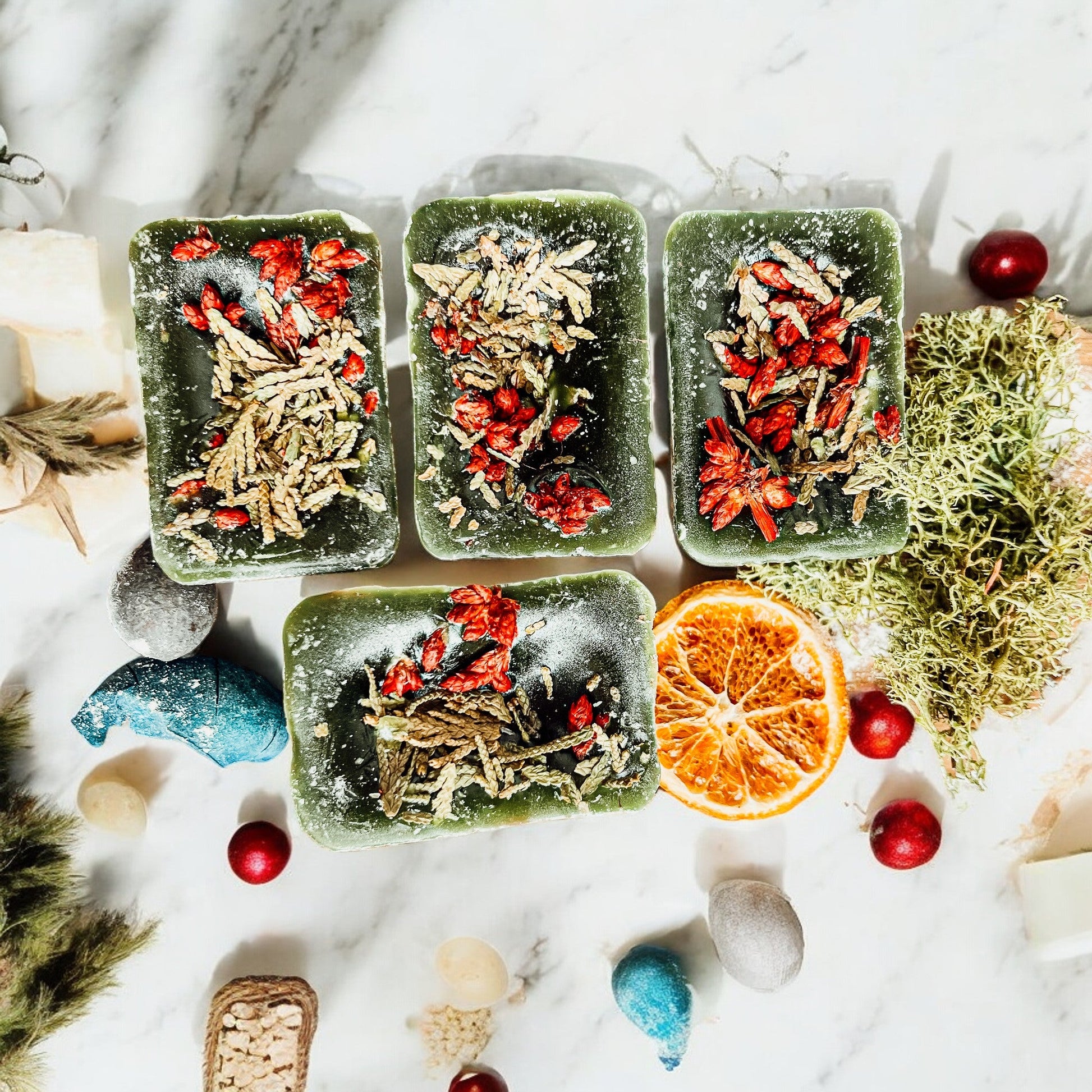 Three square green containers filled with various herbs and spices on a marble surface with decorative elements.