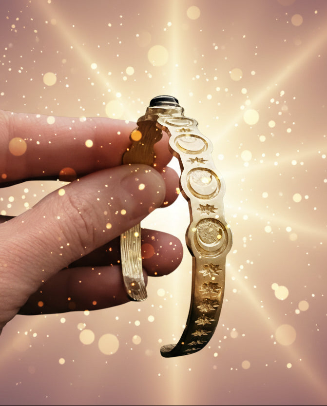 Gold bracelet held by a hand against a dark background