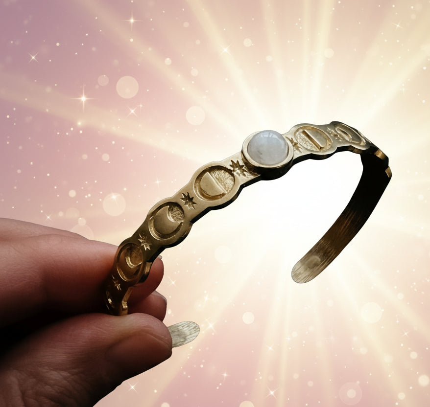Gold headband with circular designs held by a hand against a dark background