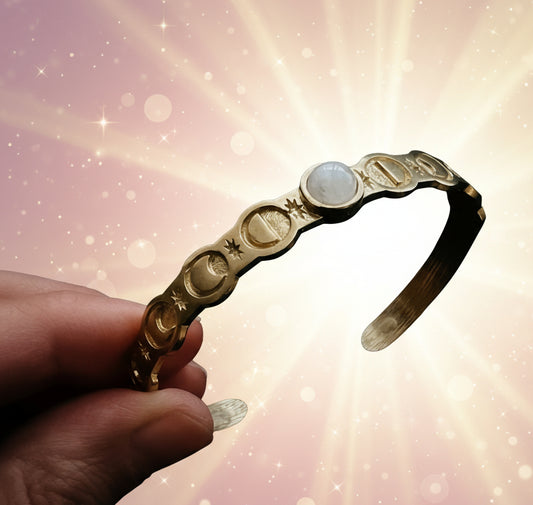 Gold headband with circular designs held by a hand against a dark background