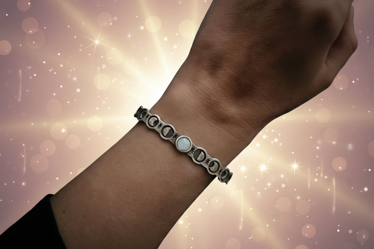 Silver bracelet with a central white stone on a wrist against a dark background