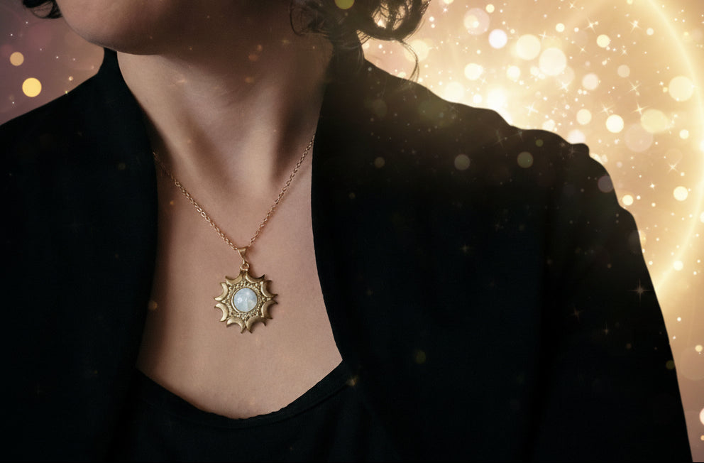 Person wearing a gold necklace with a pendant against a dark background