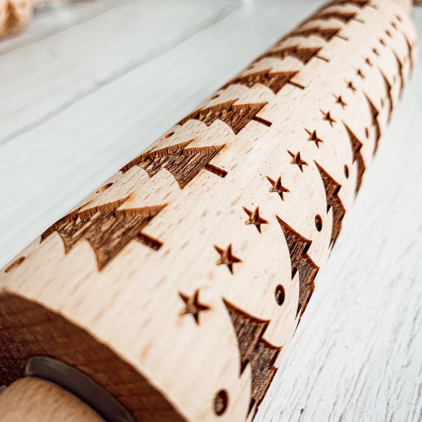 Wooden rolling pin with engraved star and arrow patterns on a light wooden surface.