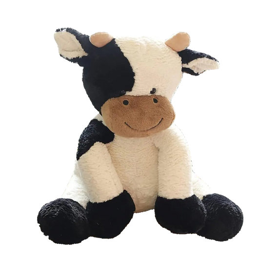 Plush cow toy sitting on a chair with a blurred indoor background