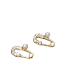 Gold safety pin earrings with pearls on a hand against a neutral background