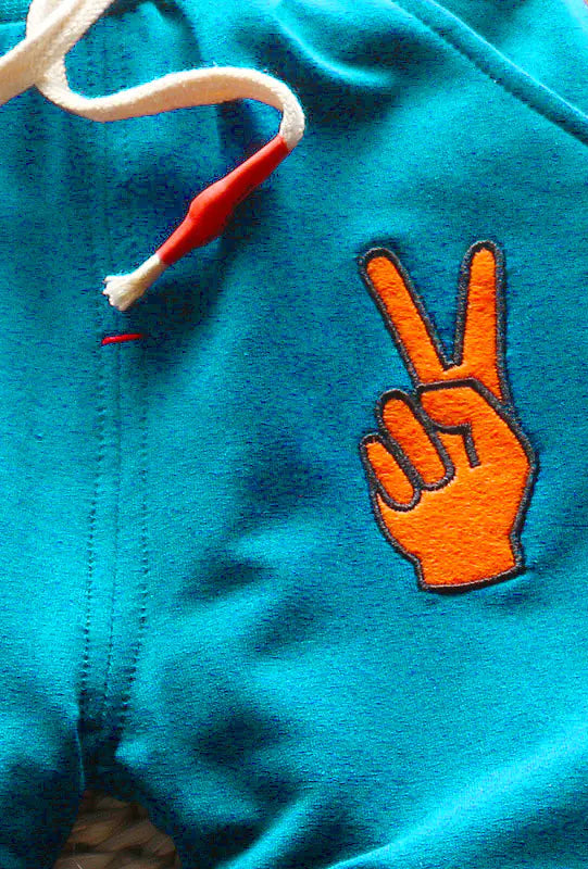 Blue pants with an orange peace sign design on a woven surface