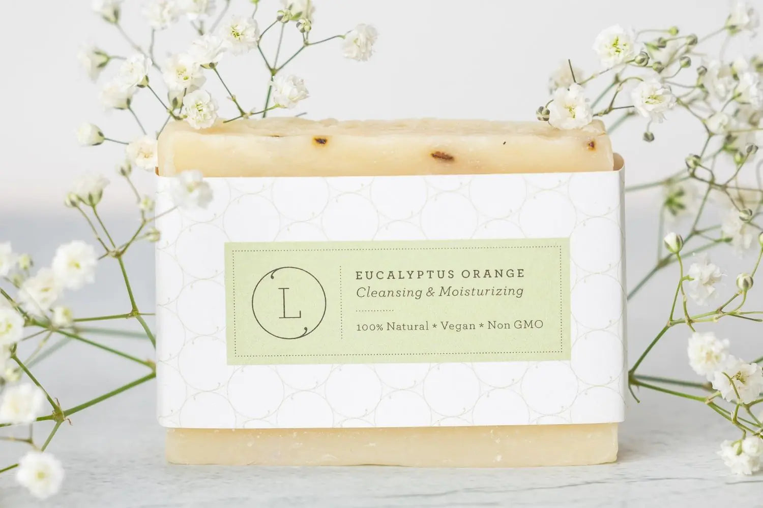 Bar of soap with a label on a light background with white flowers
