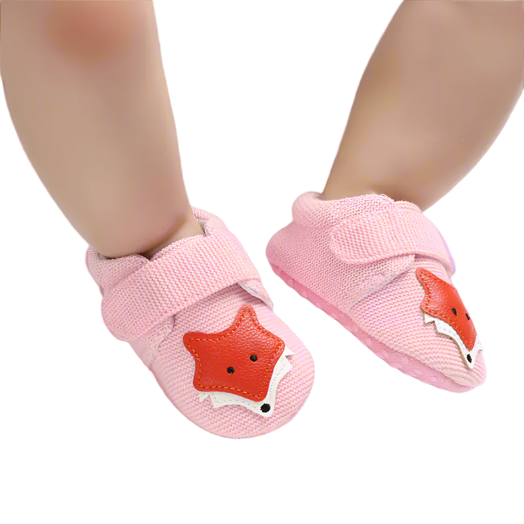 Pink baby shoes with fox design on a light background