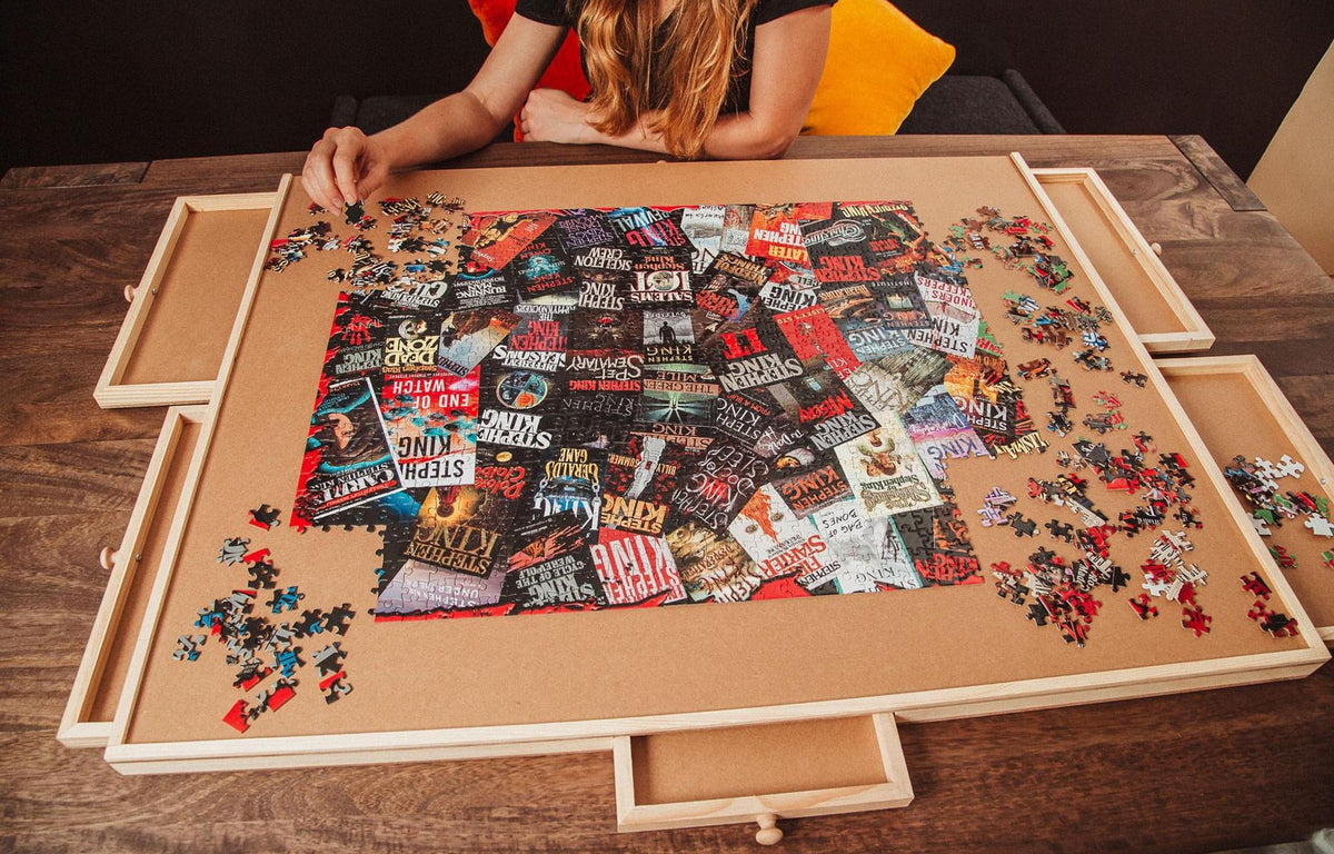 Person working on a large puzzle with a wooden tray on a table