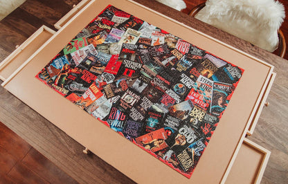 A rectangular quilt or fabric panel with a dense collage print of rock and metal album covers, displayed inside a light wood drawer on a wooden floor.