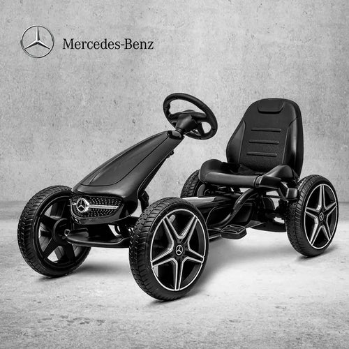 Black Mercedes-Benz pedal car on a gray concrete floor with the Mercedes-Benz logo above.