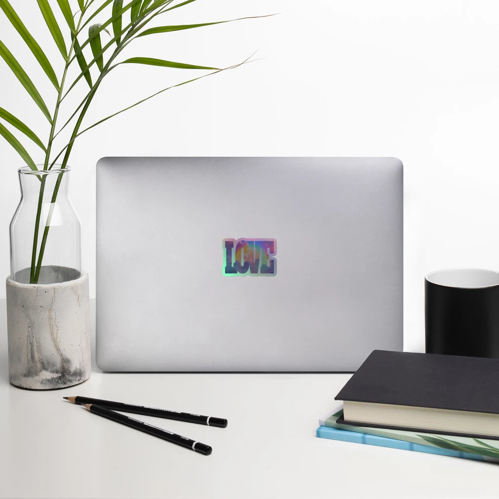 Laptop with 'LOVE' sticker on a desk with a plant, pencils, and books.