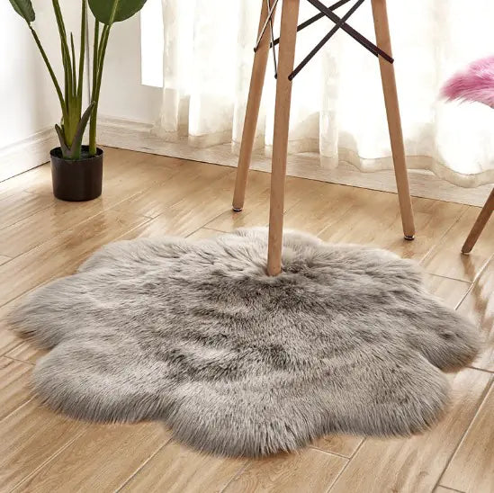 Gray fluffy rug on a wooden floor with a plant and chair in the background