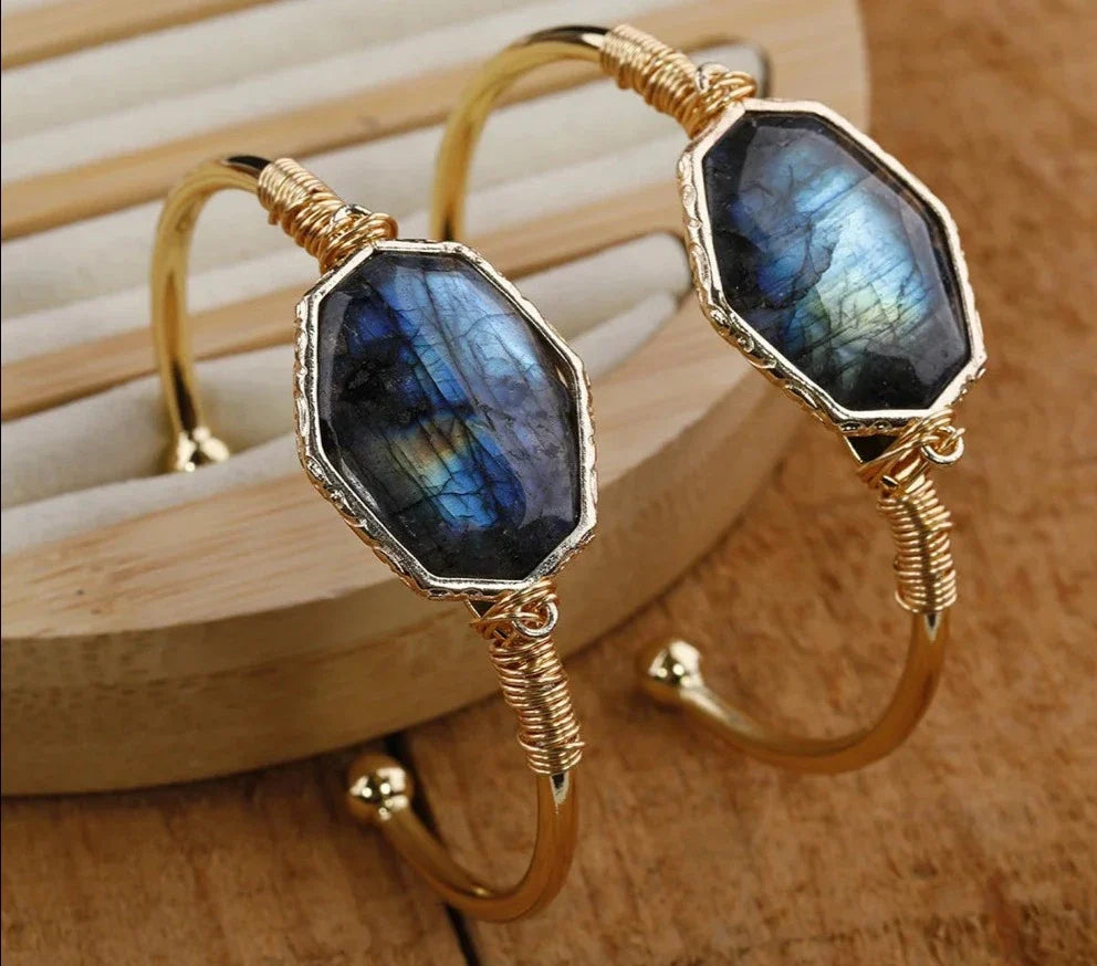 Gold hoop earrings with blue gemstones on a wooden surface
