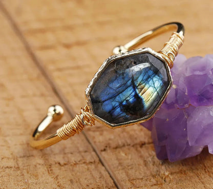Gold bracelet with a blue gemstone on a wooden surface