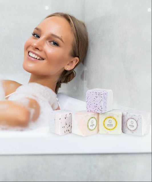 Woman relaxing in a bubble bath with bath bombs on a white background