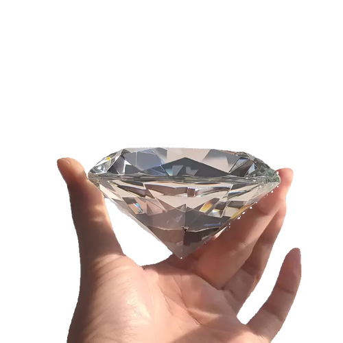Large diamond held in a hand against a white background