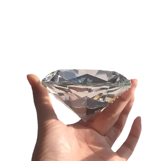 Large diamond held in a hand against a white background